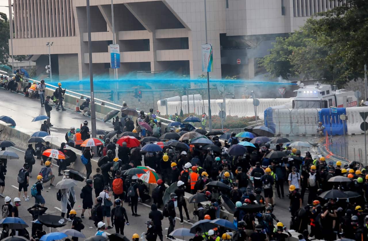 Anti-government protesters are sprayed with a water cannon during a demonstration near Central Government Complex in Hong Kong, Sunday, Sept. 15, 2019.