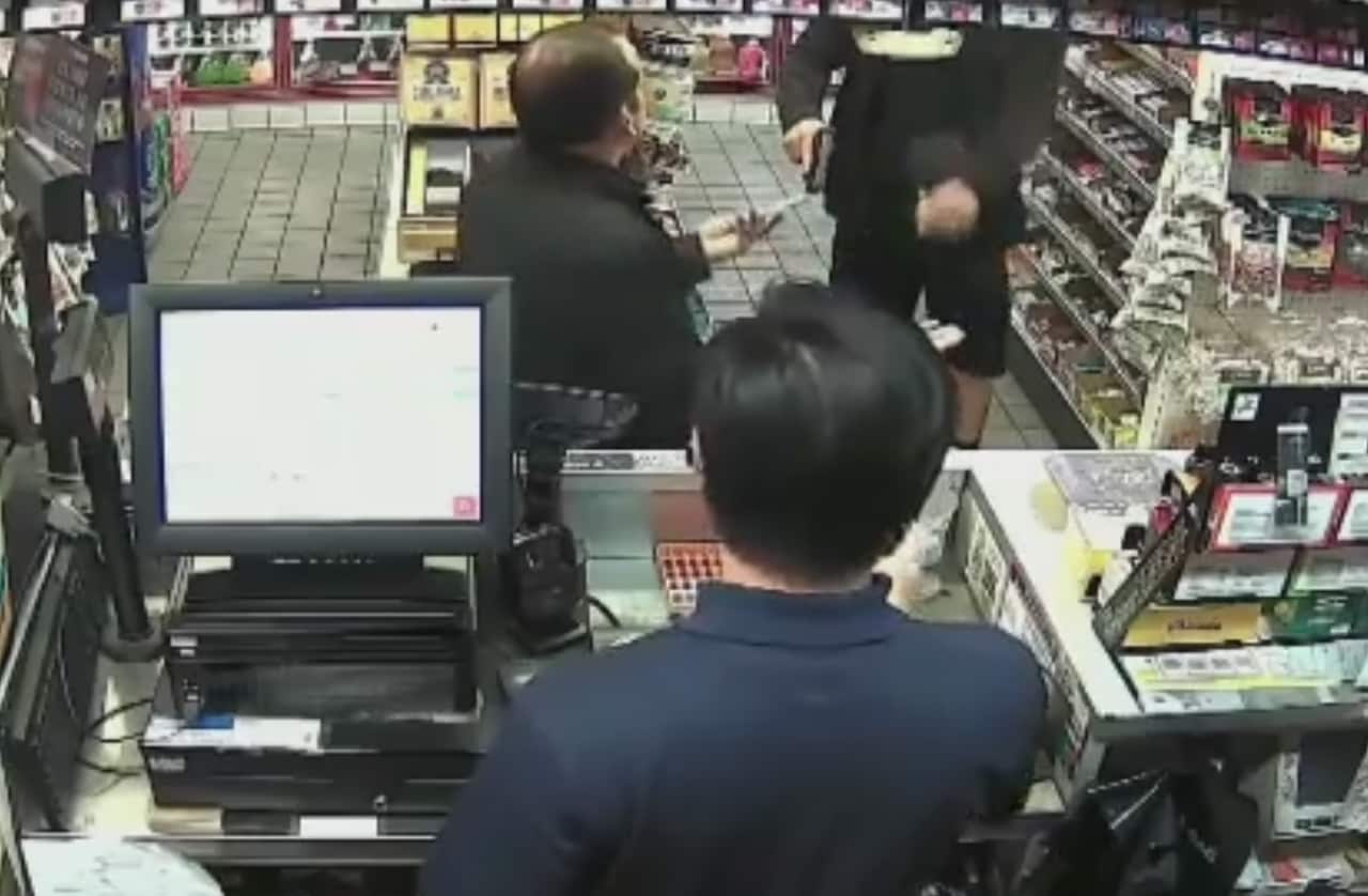 Screenshot of surveillance vision of the officer pulling his weapon out of his pocket.