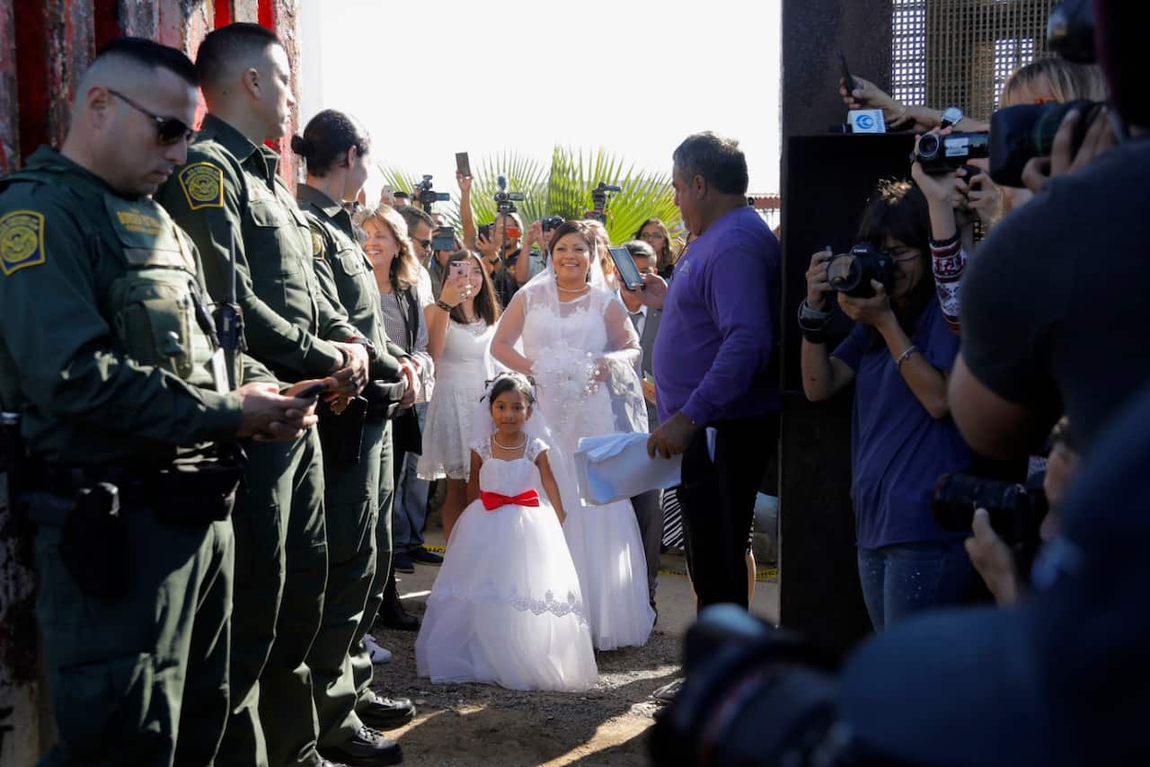 Evelia Reyes, along with her daughter, watches at the "Door of Hope", part of the for the border fence, for her fiance, Brian Houston (AAP)
