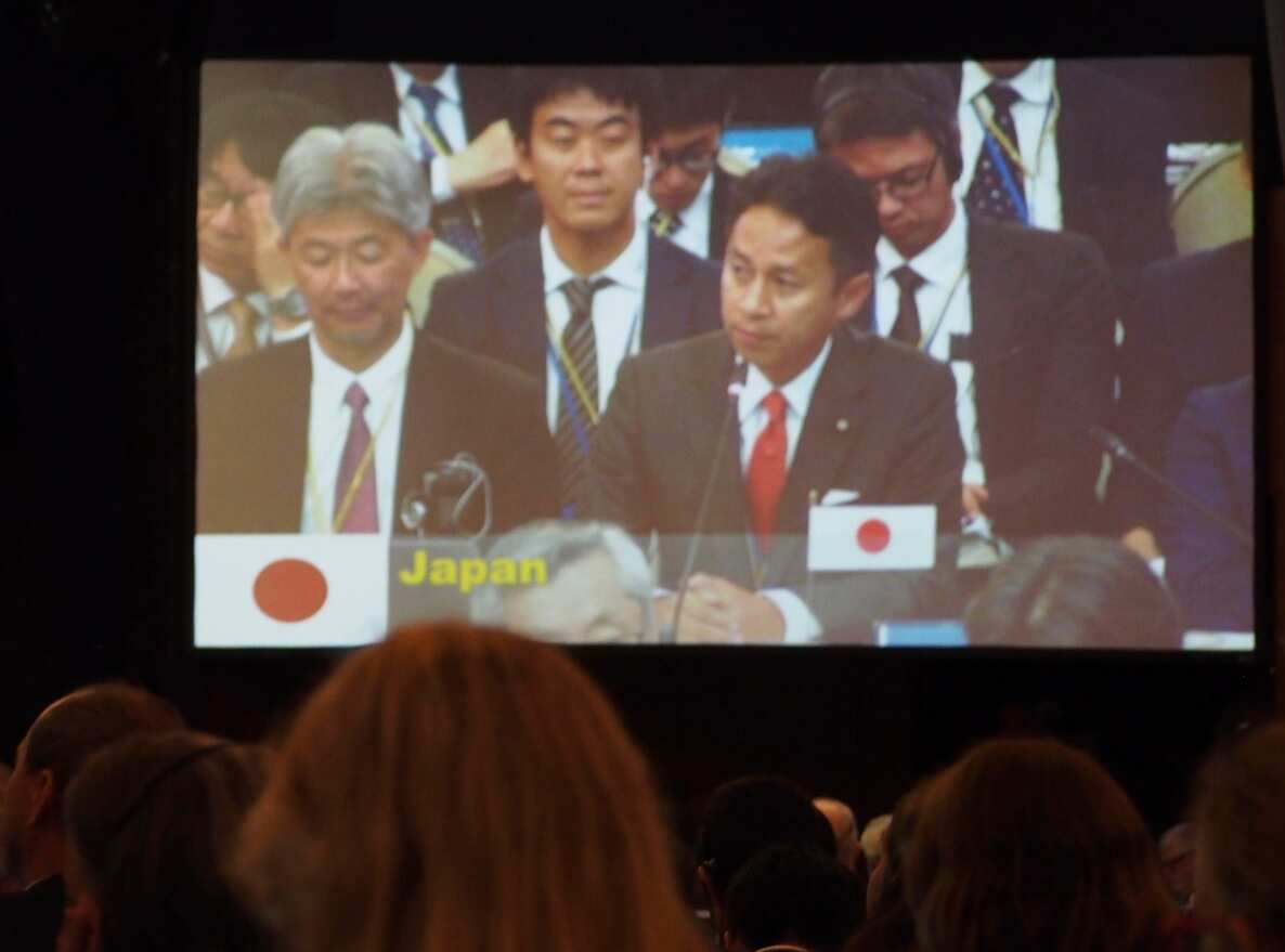 Masaaki Taniai (R), senior Japanese vice minister of agriculture, forestry and fisheries, is seen on a screen showing the plenary session