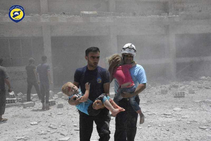 Civil defense workers carrying children after airstrikes hit a school in the western part of the southern Daraa province.