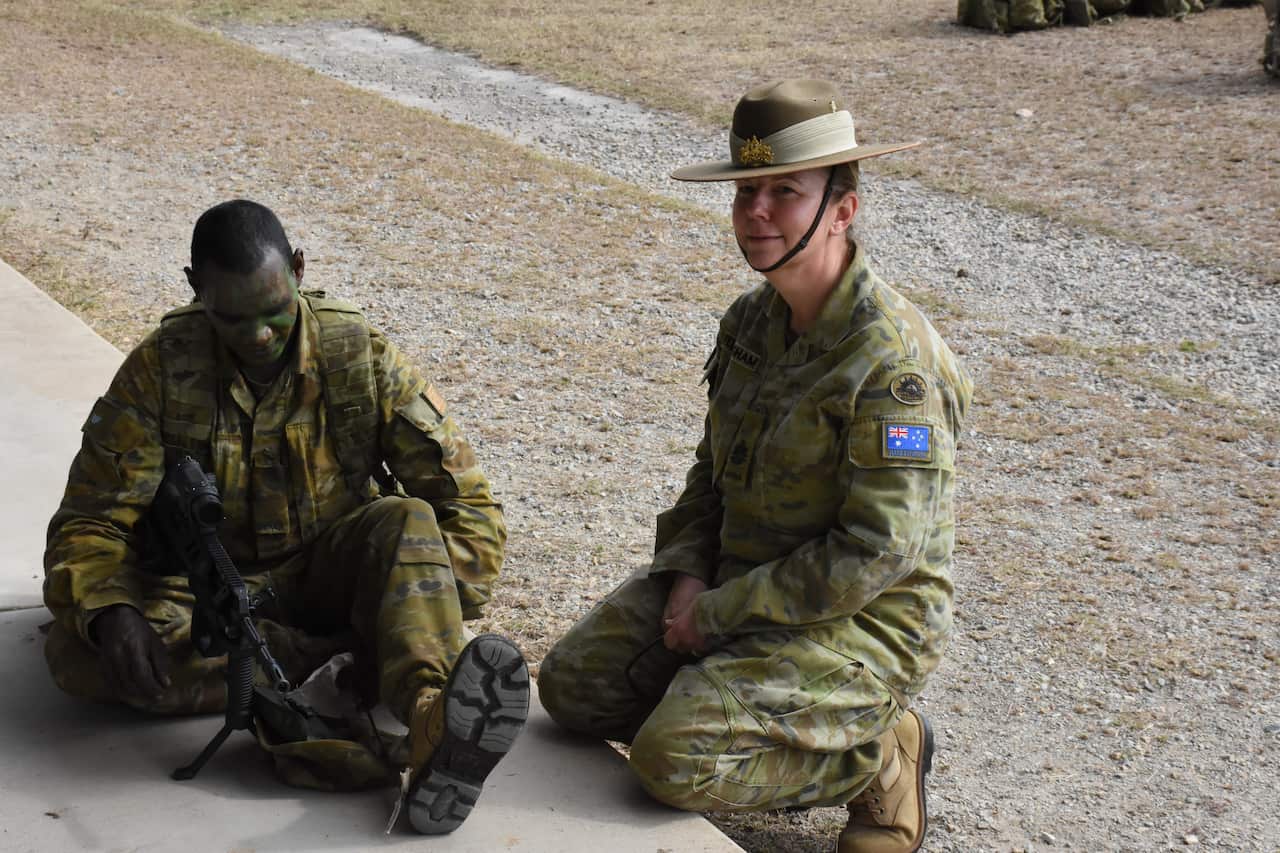 Warrant Officer Class One Kim Felmingham chats with Private Jordan Barmey as he cleans his weapon after a day on the rifle range.