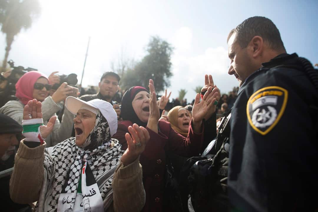 Palestinian women protest next to an Israeli police officer outside the Old City.