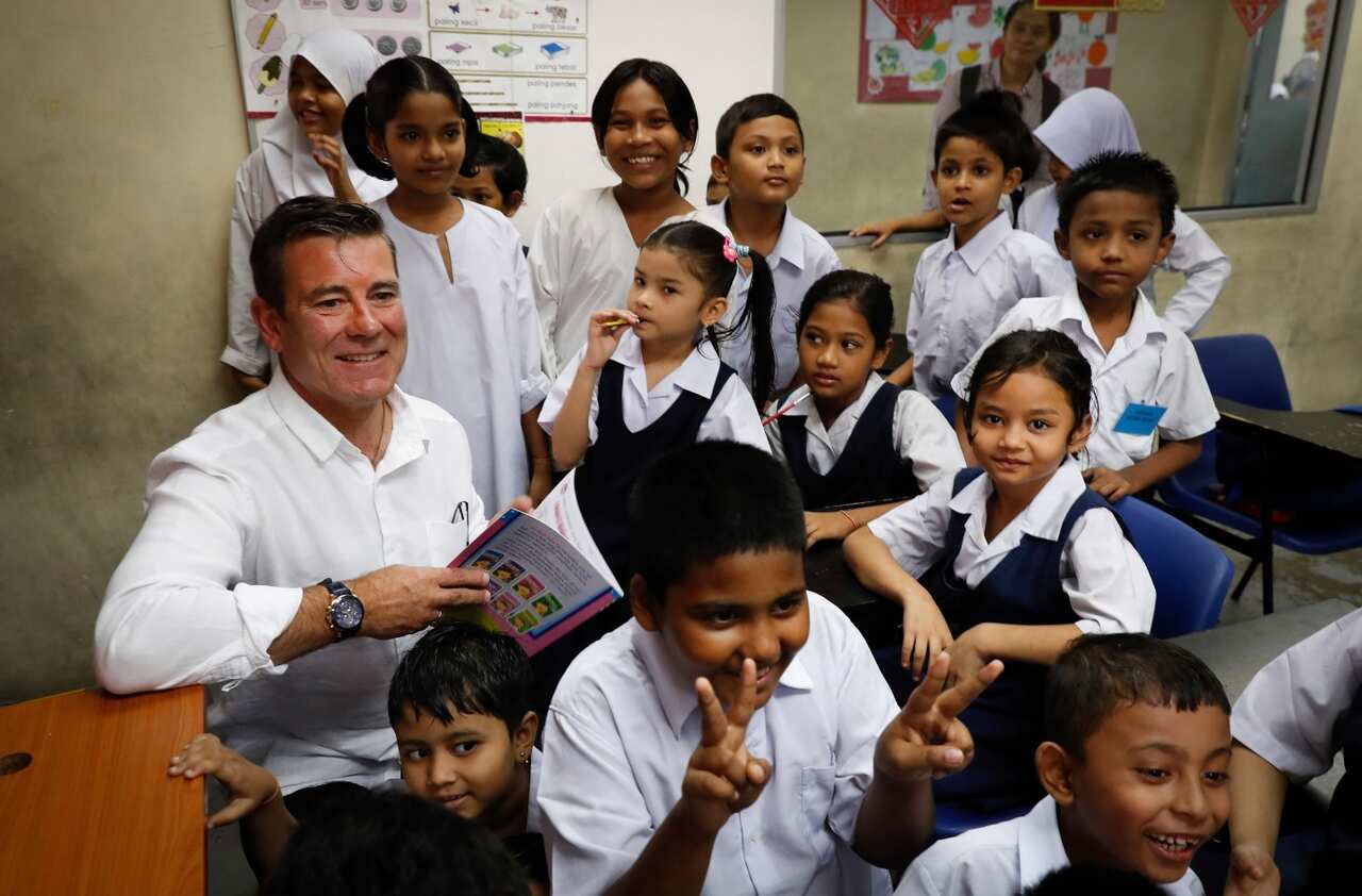 File: New Zealand Immigration Minister Michael Woodhouse, left, smiles as he interacts with refugee students during his visit to the UNHCR Tzu Chi Centre