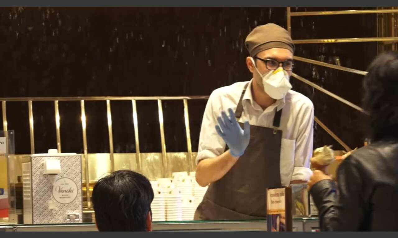 Hospitality workers wear protective masks while serving customers who have ventured out in Rome.
