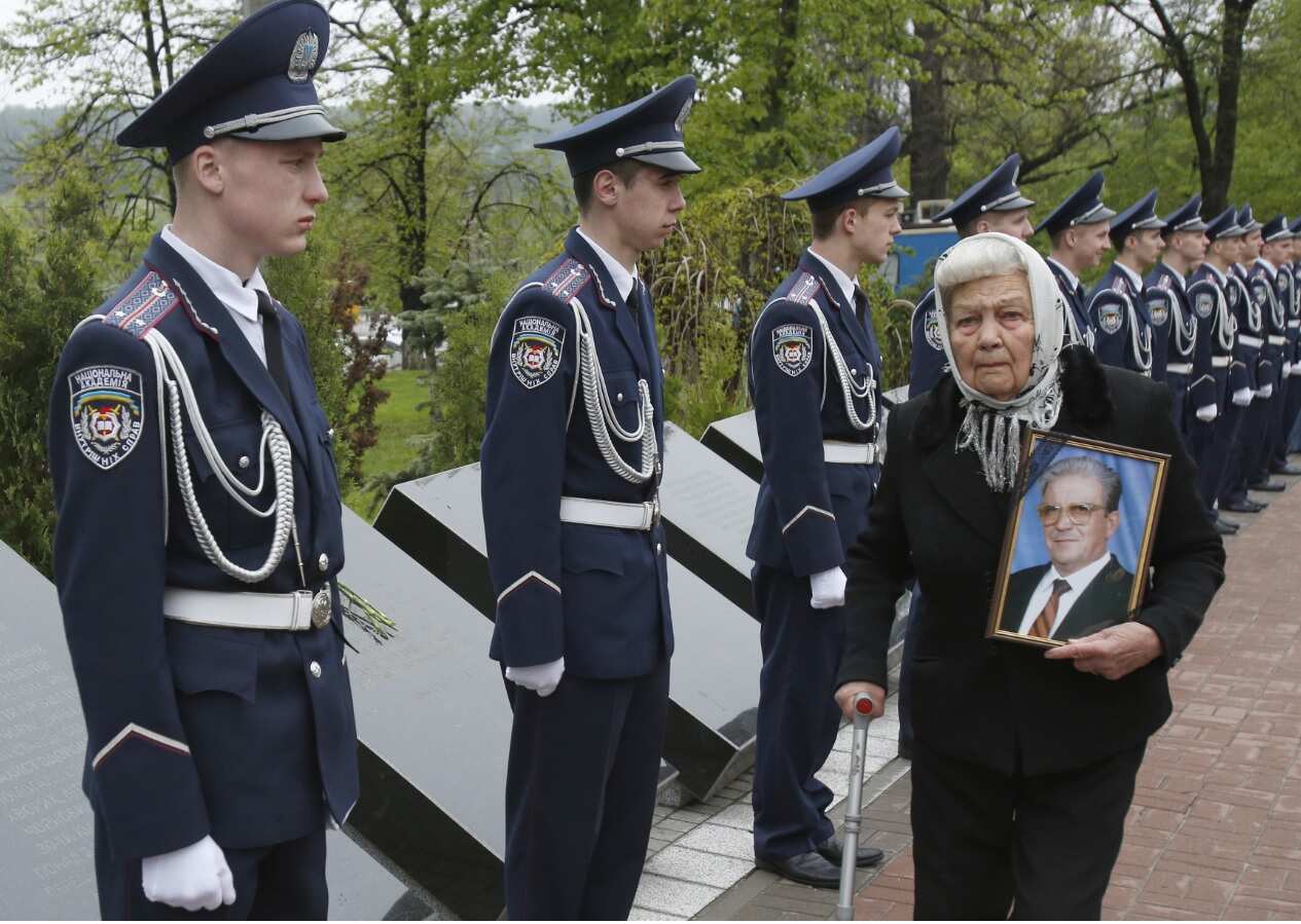 A elderly woman carries a portrait of her relative, a victim of the Chernobyl nuclear disaster, at the Chernobyl victims' memorial in Kiev (Getty)