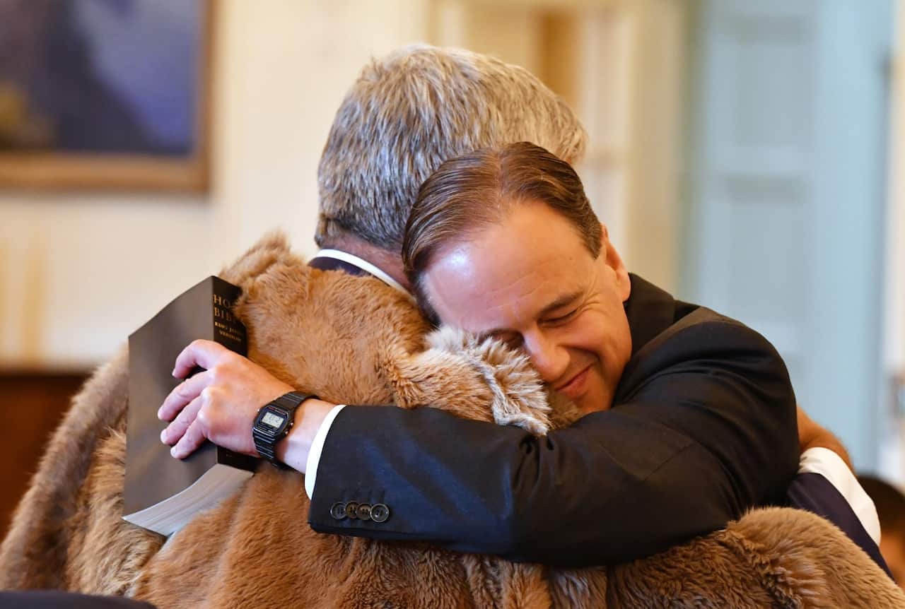 Minister for Industry Greg Hunt (R) hugs Minister for Indigenous Health and Aged Care Ken Wyatt at a swearing-in ceremony at Government House in Canberra