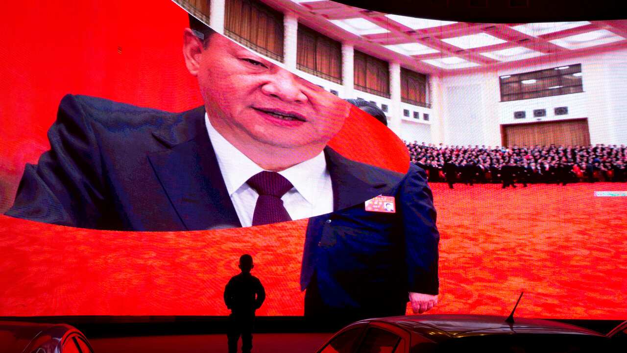 A child stands near a large screen showing photos of Chinese President Xi Jinping near a carpark in Kashgar in western China's Xinjiang region on 3/12/18.