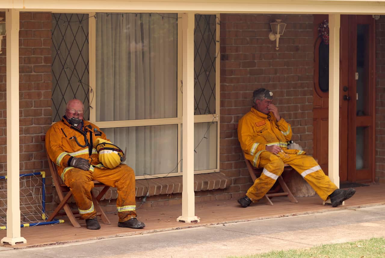 Exhausted Country Fire Service volunteers catch a short break while battling the Adelaide Hills fire on Friday afternoon.