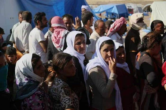 Displaced Iraqis from the Yazidi community gather for humanitarian aid at Nowruz camp, in Derike, Syria. 