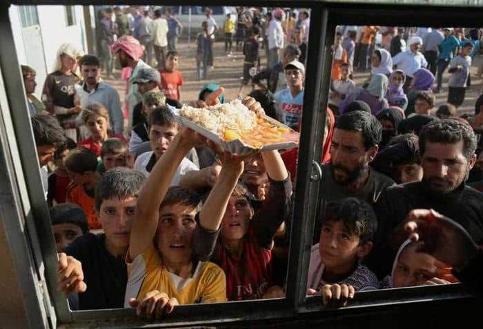Displaced Iraqis from the Yazidi community gather for food at the Nowruz camp, in Derike, Syria.