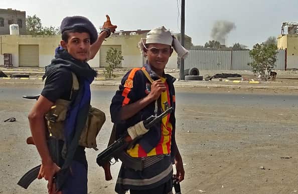 A member of the Yemeni pro-government forces points to smoke rising from the city centre.