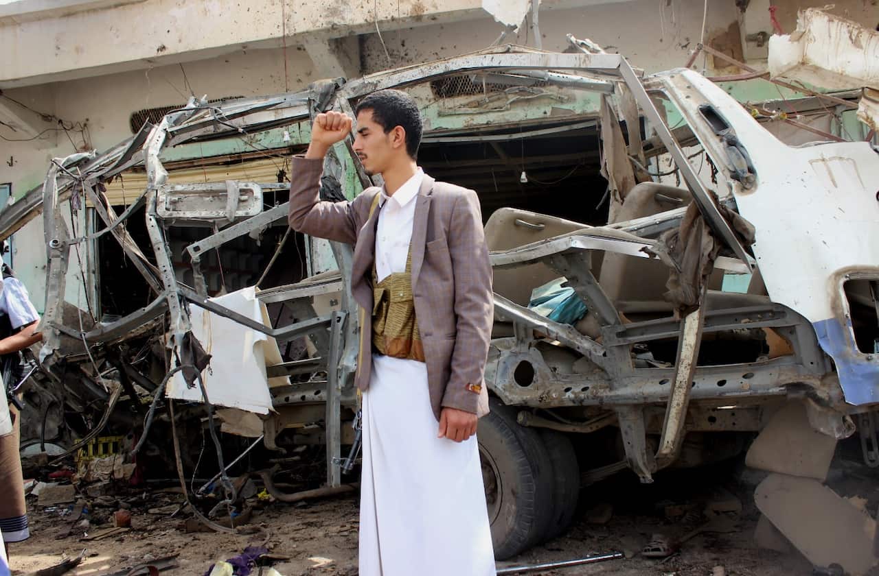 A Yemeni stands near a destroyed bus at the site of a Saudi-led airstrike.