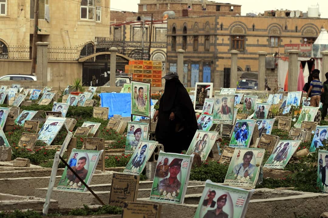 A Yemeni woman walks amongst portraits on the grave of Houthi militia members allegedly killed in ongoing fighting.