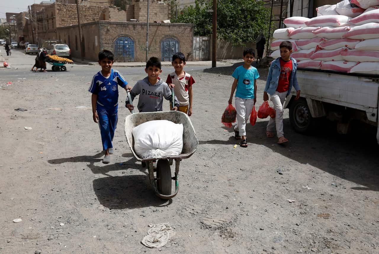 Yemeni children hold food items at a street in Sanaa, 1 April 2020.