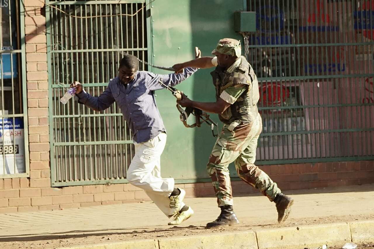 A Zimbabwean soldier beats a man in a street of Harare.