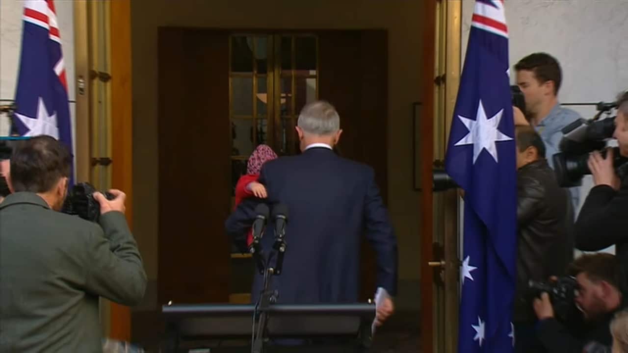 The outgoing PM departs from the media conference, with grandson Jack over his shoulder.