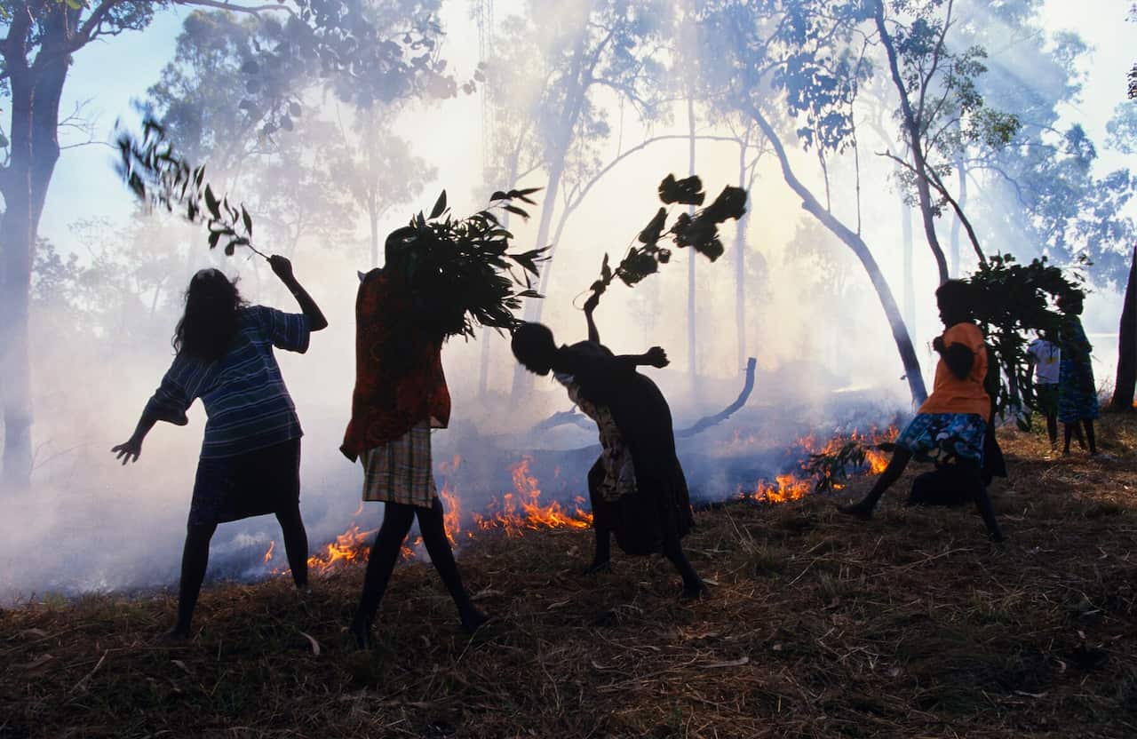 Australia - Arnhem Land - Northern Territory - Aboriginal children from Ramingining school beat out an approaching bushf