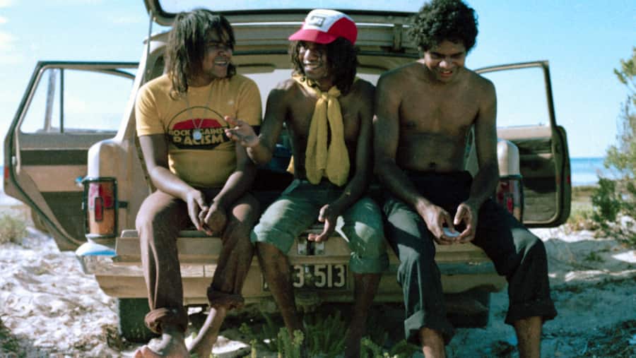 Classic photo of No Fixed Address band members Jon Jon, Bart and Ricky taking a break during the filming of 'Wrong Side of the Road' at Point Pierce, 1980