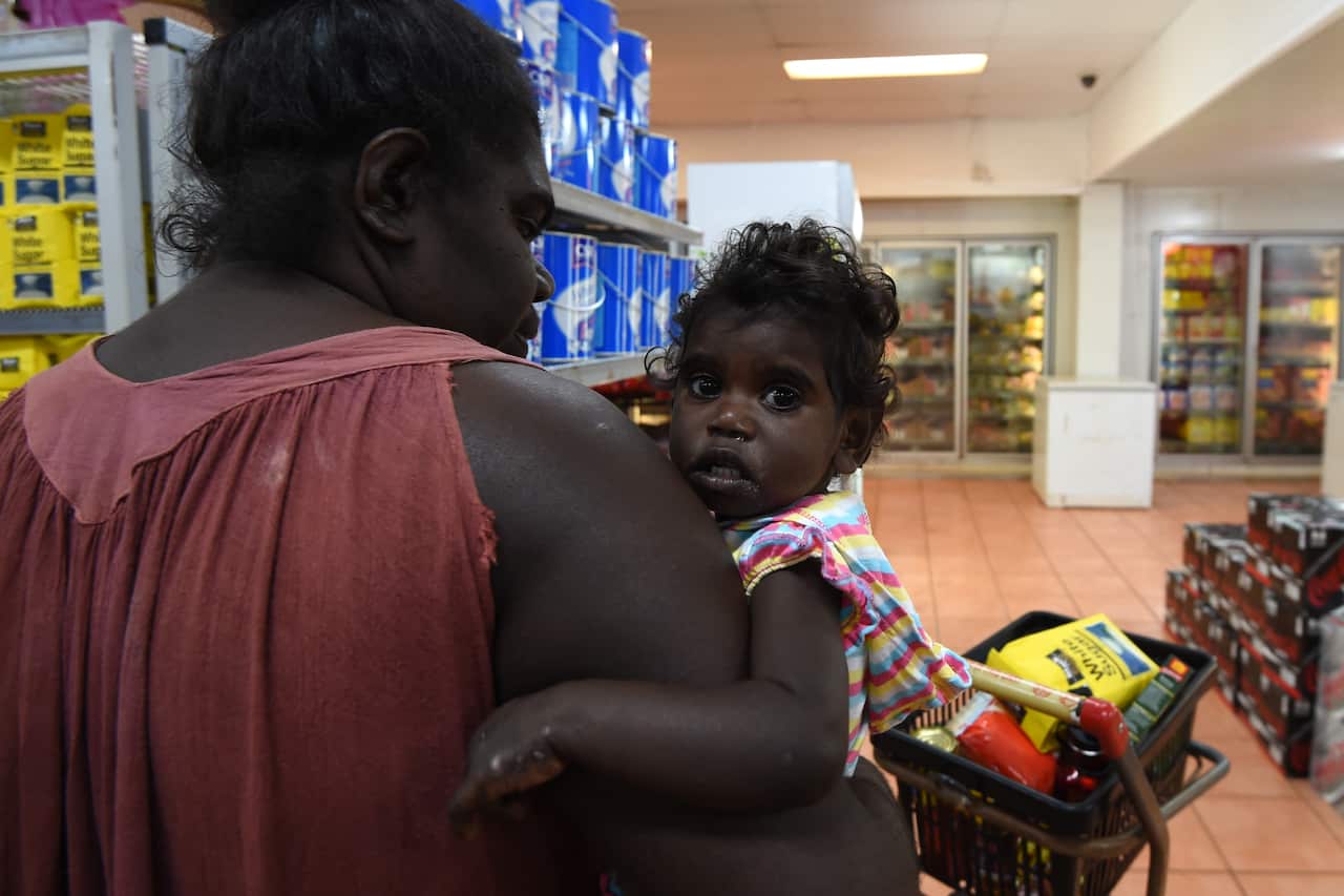 Resident with her baby shopping at the general store in Milingimbi in the Northern Territory      