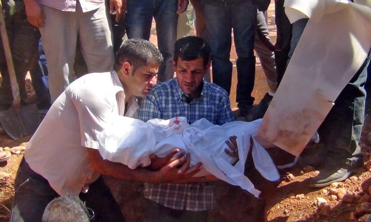 father of the drowned three-year-old boy Aylan Kurdi from Syria, holds his son's body as they burry drowned migrants during a funeral in Kobane, Syria,