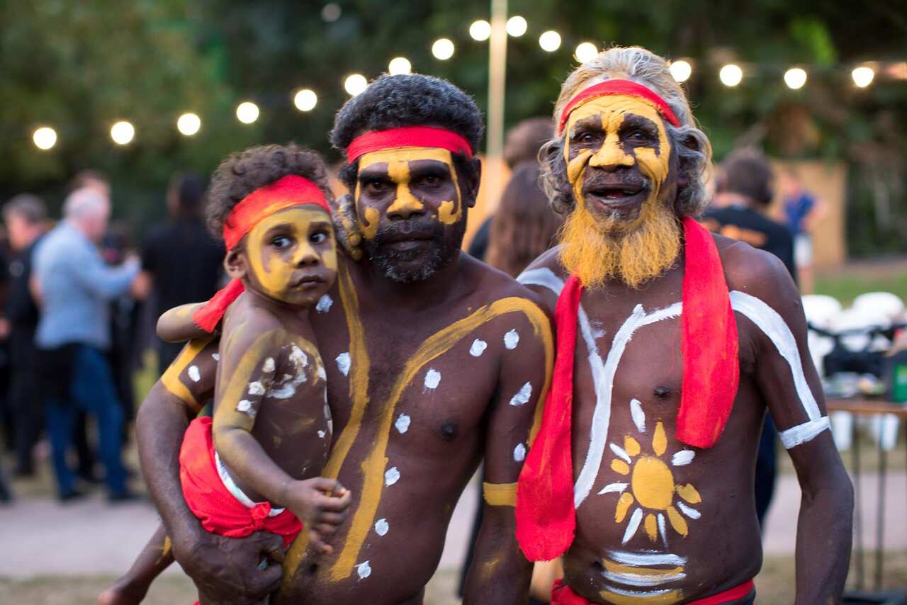 A family in traditional paint smiles for the camera. 