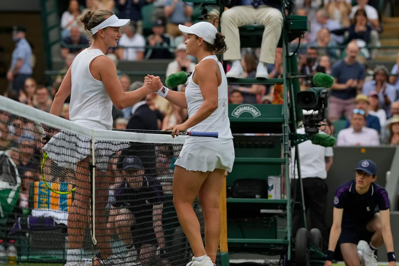 Ashleigh Barty, right, holds hands with Czech Republic's Barbora Krejcikova after winning the women's singles fourth round match on day seven of the Wimbledon Tennis Championships in London, Monday, July 5, 2021