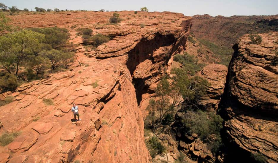 Photographer Andrew Gregory stands above the Garden of Eden at Kings Canyon in Watarrka National Park; he is preparing to fly his UAV copter through the narrow gap and up against the sheer canyon walls. The Garden of Eden penetrates into the water table a