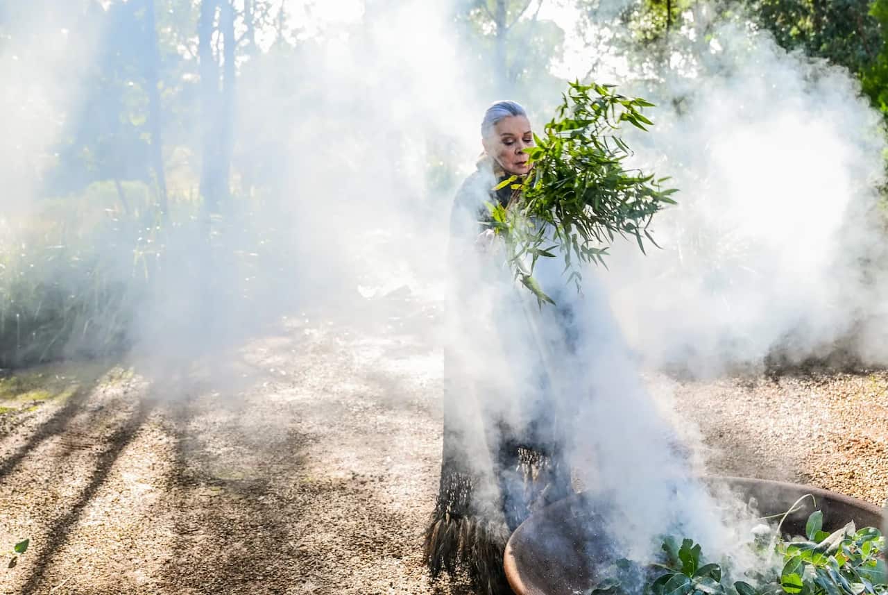 Lois peeler surrounded by smoke in the woods during a ceremony