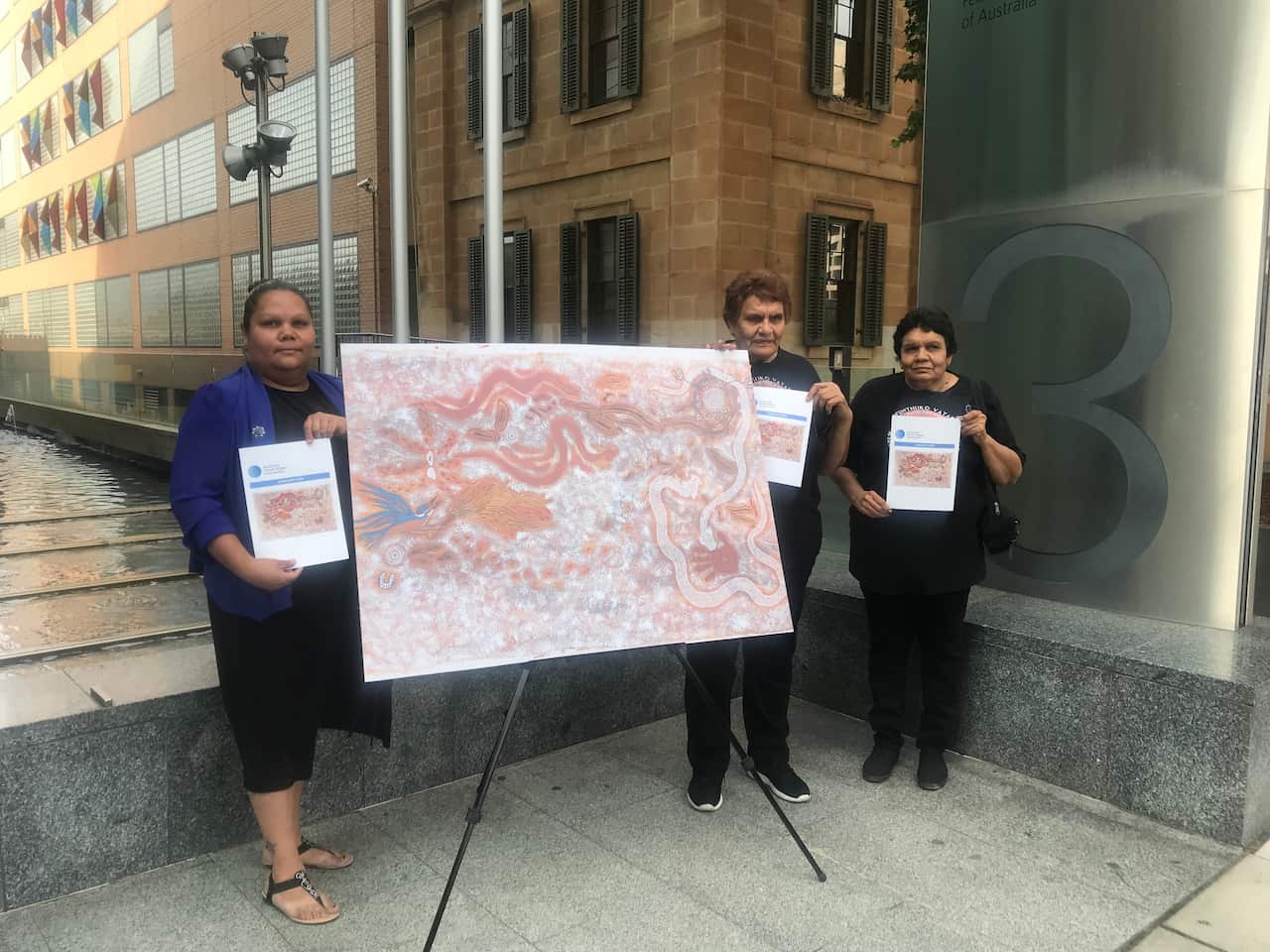 Adnyamathanya women hold a painting depicting a cultural site near the proposed nuclear waste facility. 