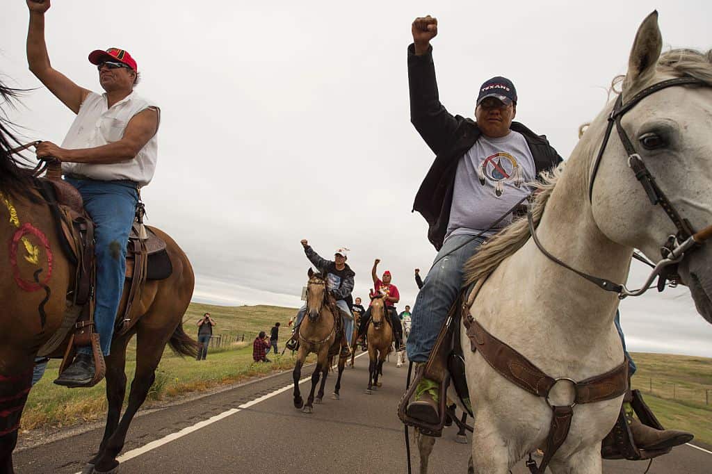 Native Americans ride with raised fists to a sacred burial ground that was disturbed by bulldozers building the Dakota Access Pipeline.