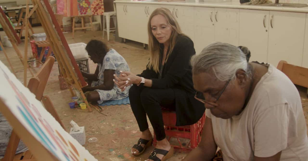 Karla Grant sits with two women who are painting