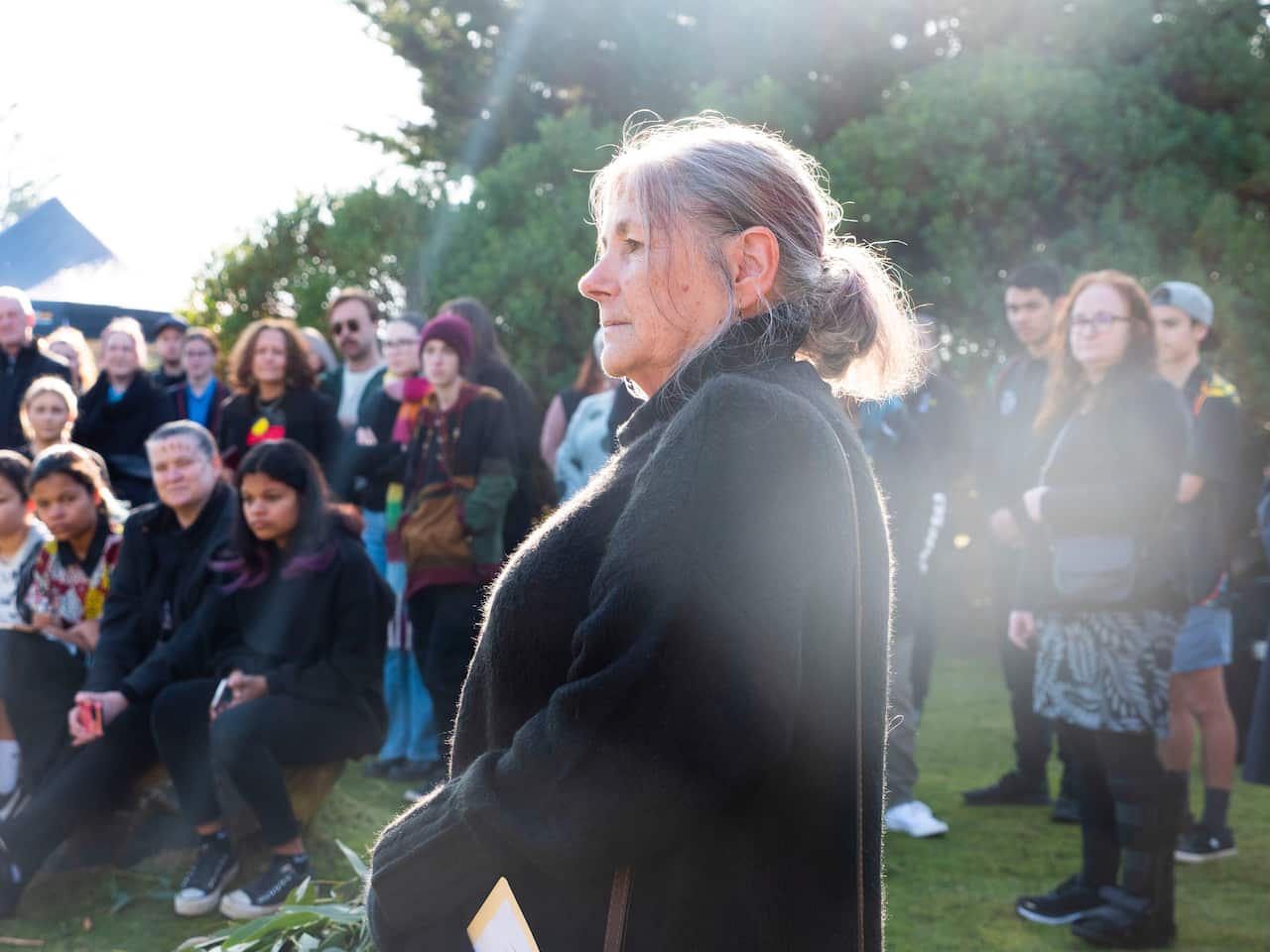 A woman standing outside with crowd behind her