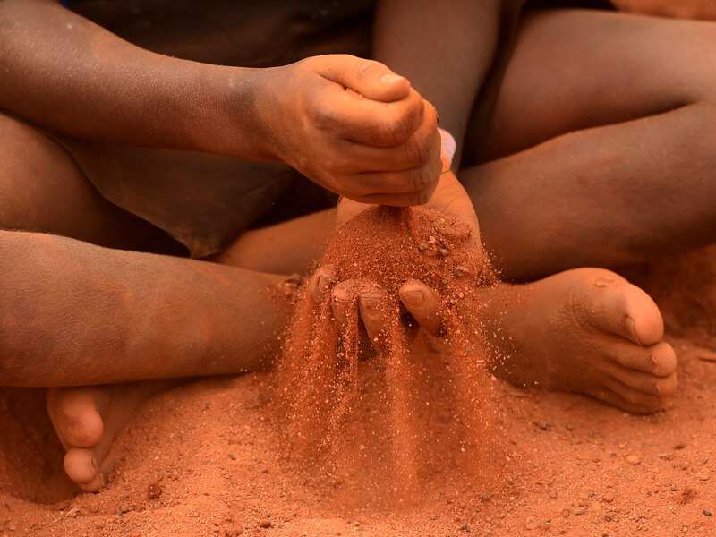 An indigenous child plays in red sand