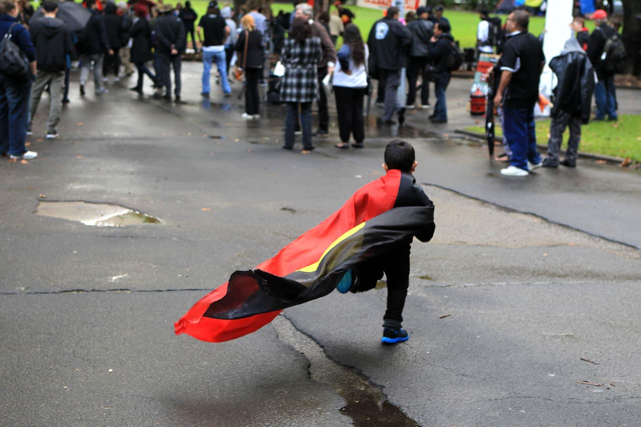 Aboriginal boy wears Aboriginal flag as cape