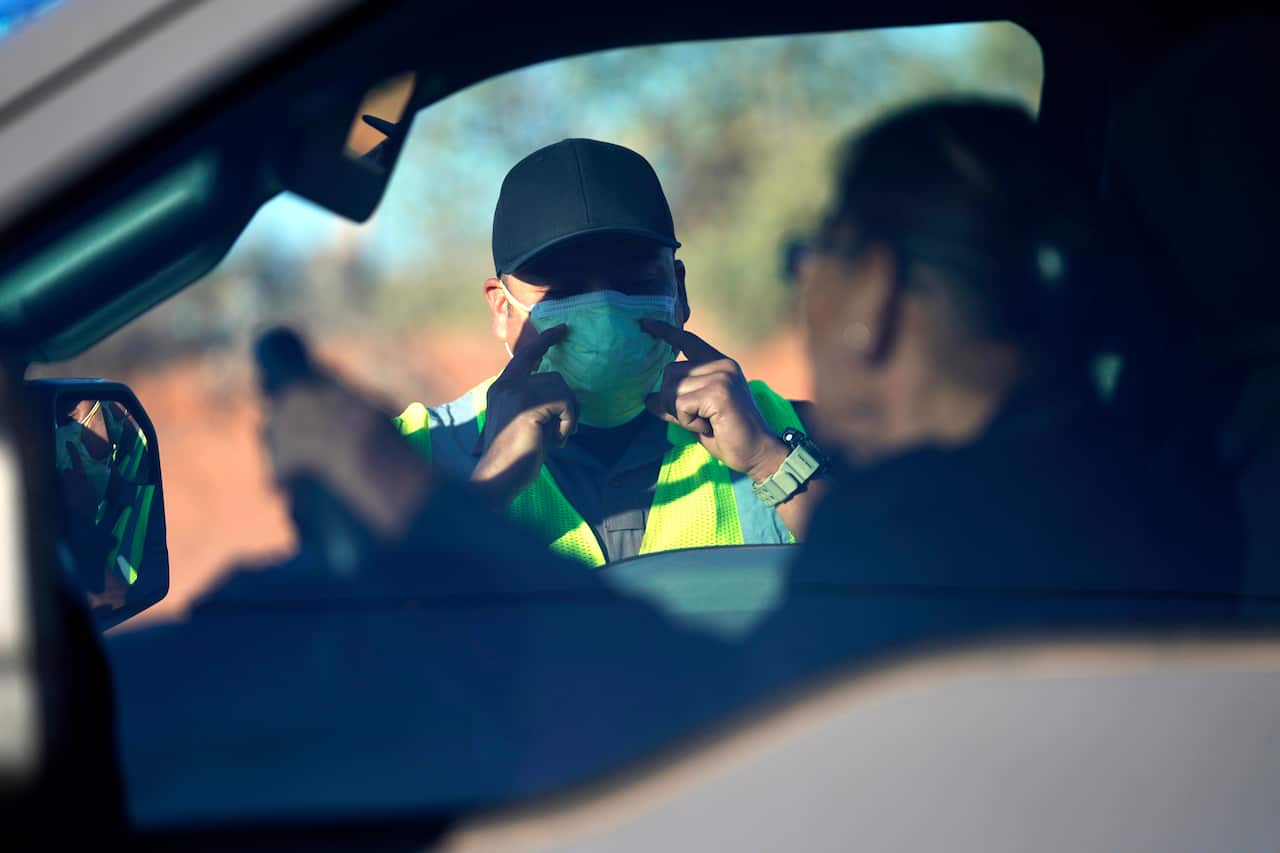 An officer with the Navajo Nation Police talks to a driver at a roadblock on the Navajo reservation.