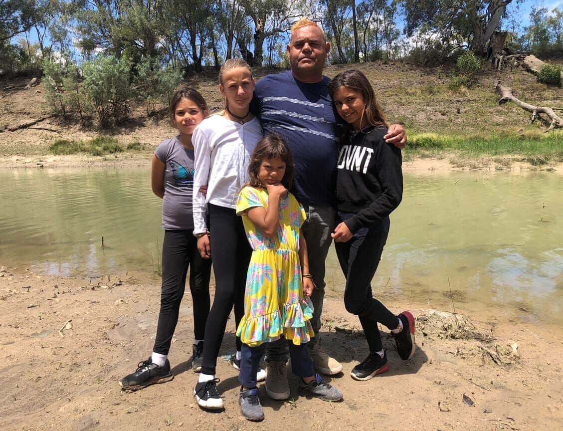 Owen Whyman and his family standing by the Darling River which flows through their town of Wilcannia/
