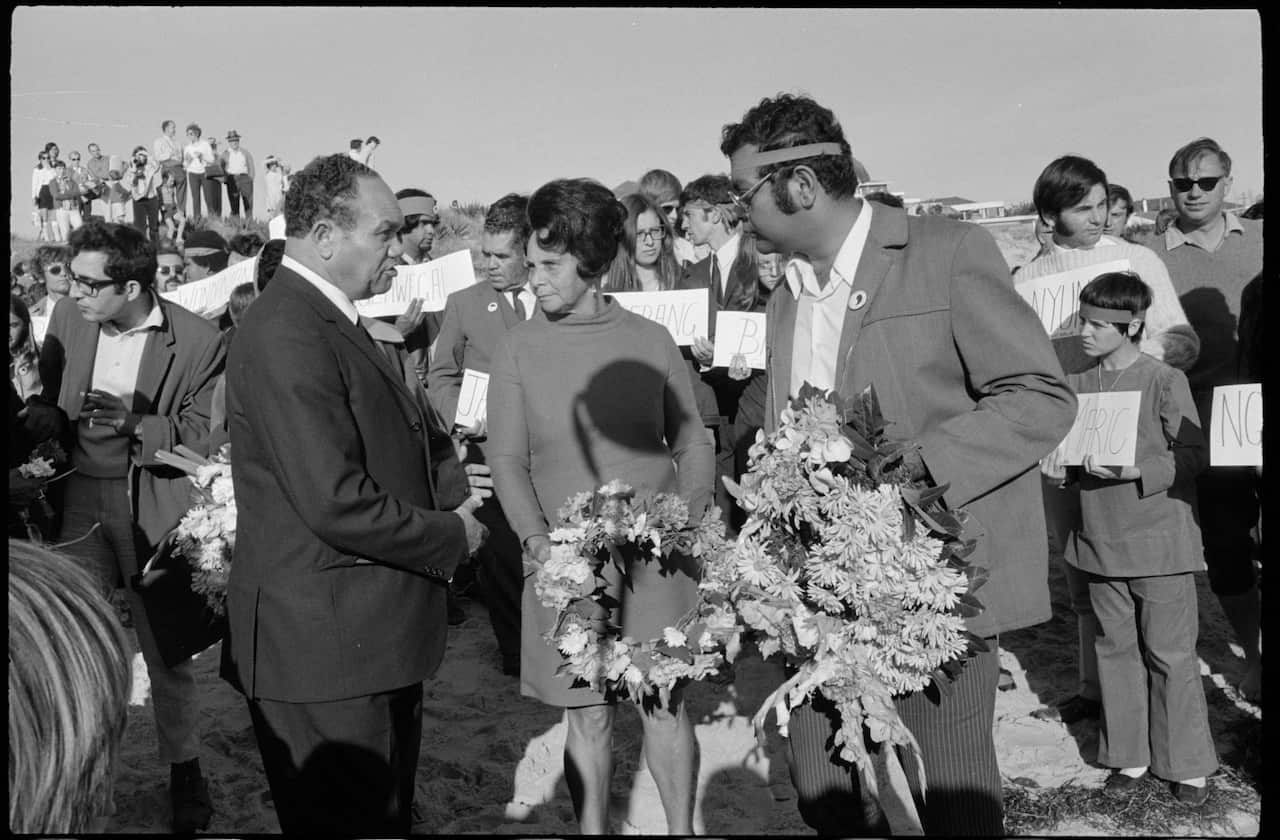 black and white photo of Aboriginal protestors holding wreaths on a beach