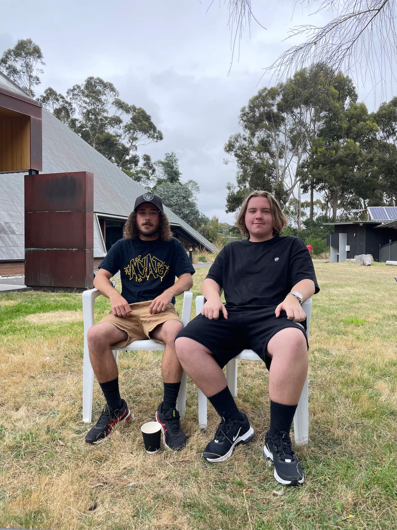 Brothers Seth Counsel, 19 yrs old and Blake Counsel, 14 yrs old sit on chairs at the outdoor broadcast of Online Invasion Day Rally 2022 Lutruwita/Tasmania at piyura kitina (Risdon Cove)