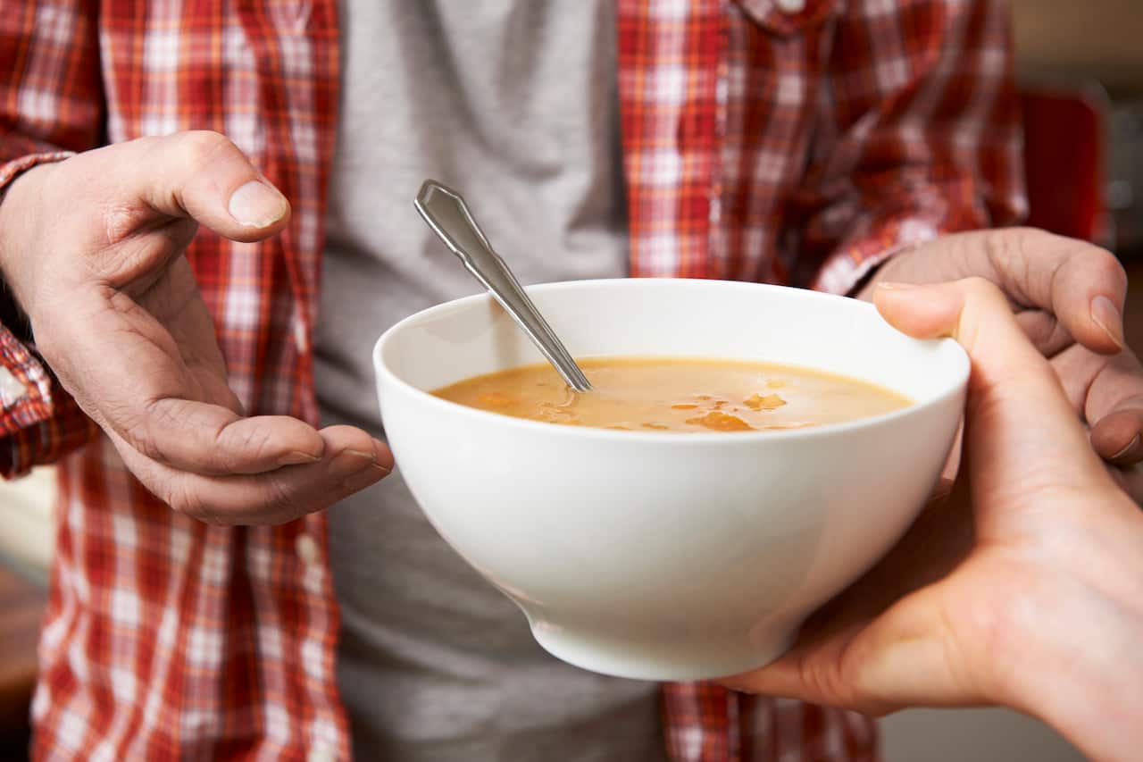 A man being handed a white bowl of soup