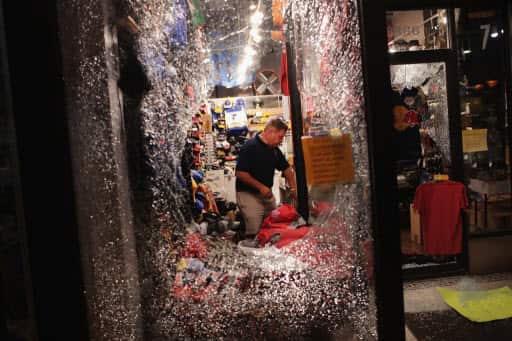 A worker cleans up broken glass from a window smashed during a protest.