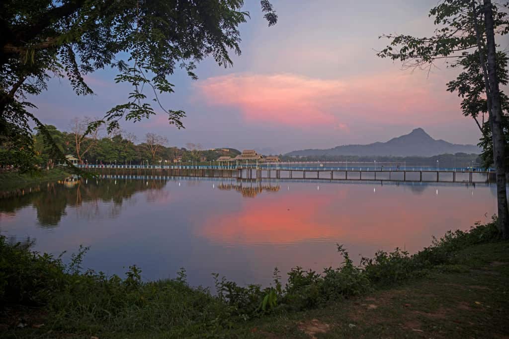 Wooden bridge over Kan Thar Yar Lake at sunset.