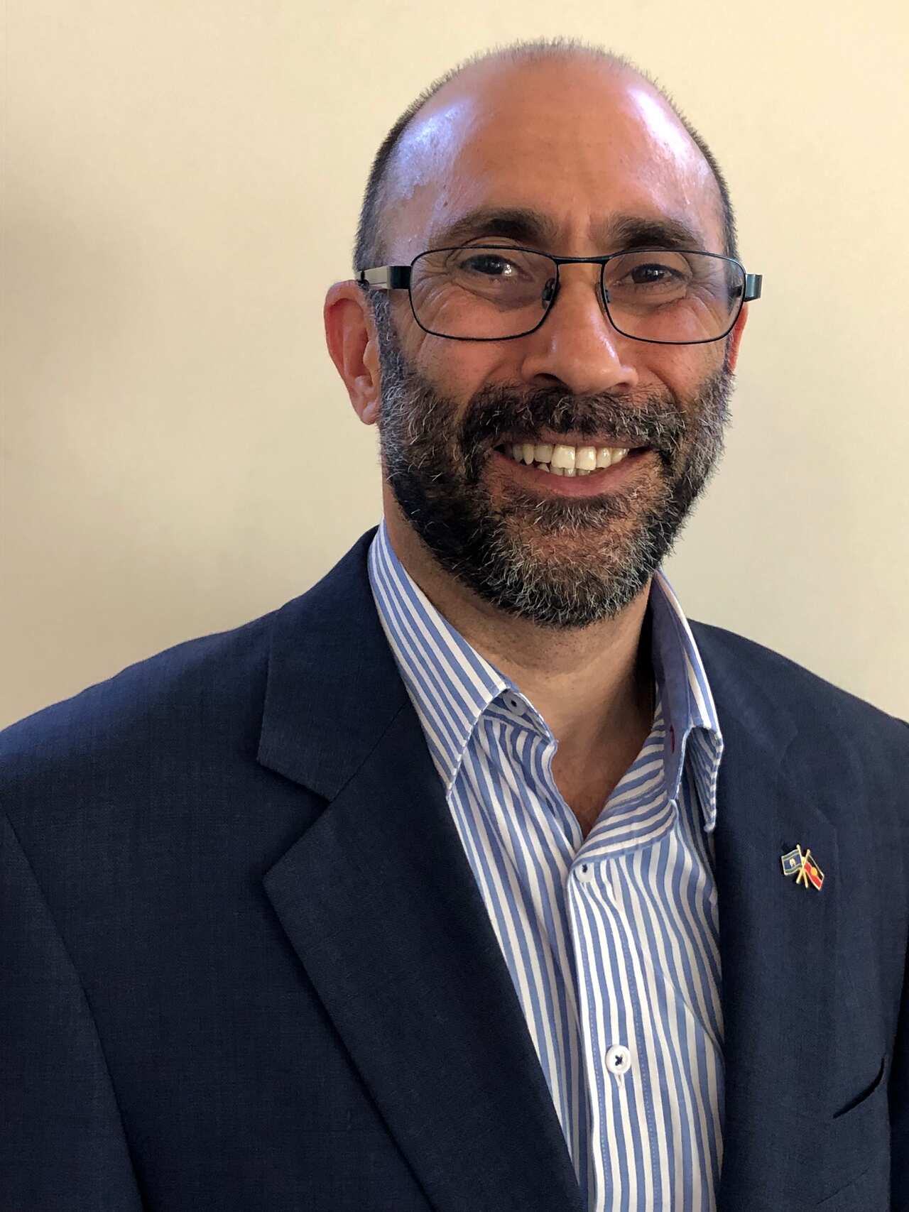 A man wearing glasses and a suit is smiling