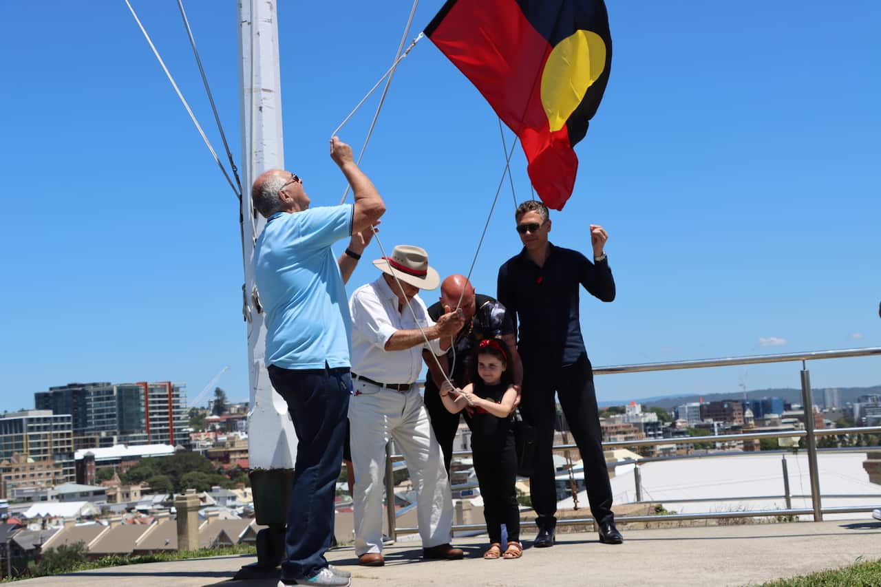 Isla Johnson helps raise the Aboriginal flag at Fort Scratchley for the first time.