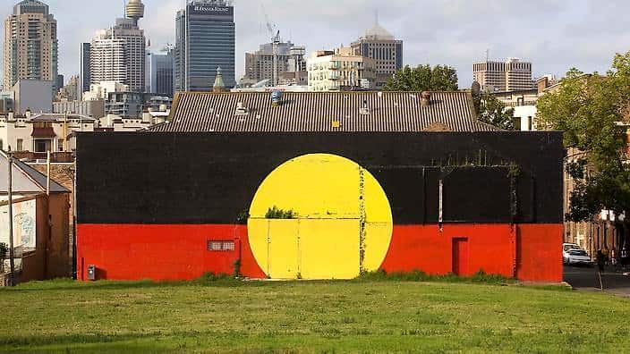 An Aboriginal flag mural is pictured in front of the Sydney skyline in Redfern, Sydney, Australia, Monday