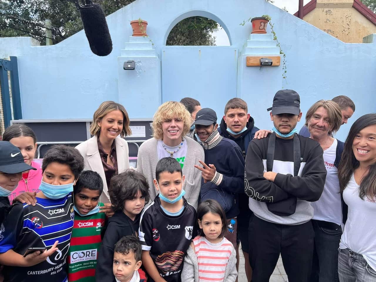 A crowd of youth surround the Kid LAROI for a photo