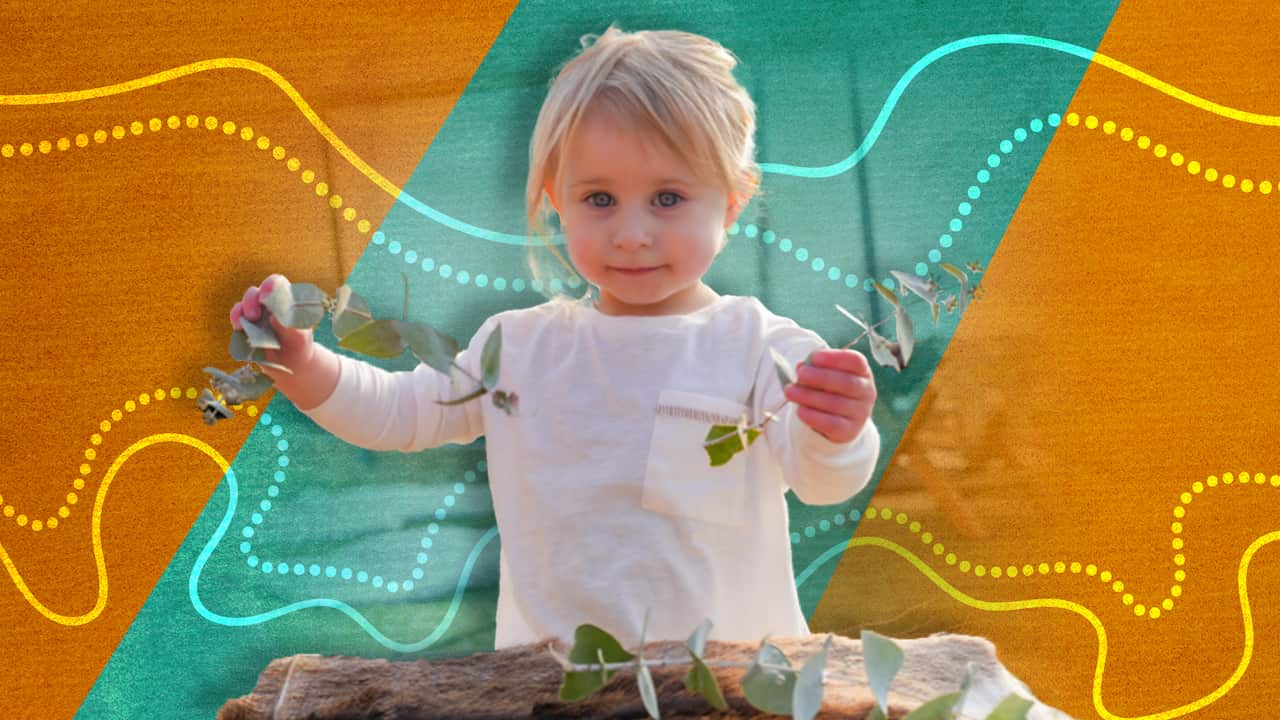 A toddler playing with leaves outside