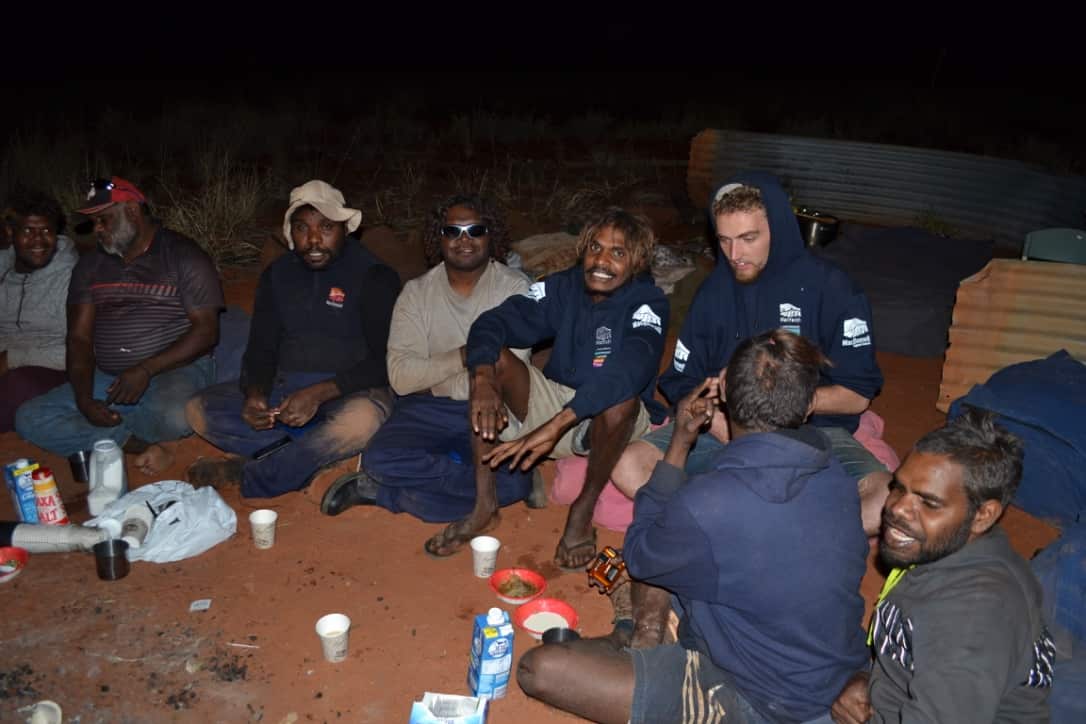 The men enjoy a hot meal and a cup of tea as they share a yarn around a warm camp fire.