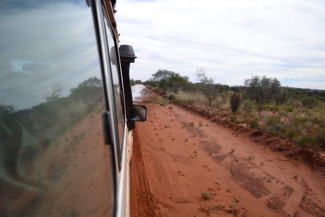 Out of the rear window the road ahead appears flooded out. The foot tracks left in the soft sand are from a passenger who was sent ahead to gauge the water depth and if it’s safe enough to pass. 