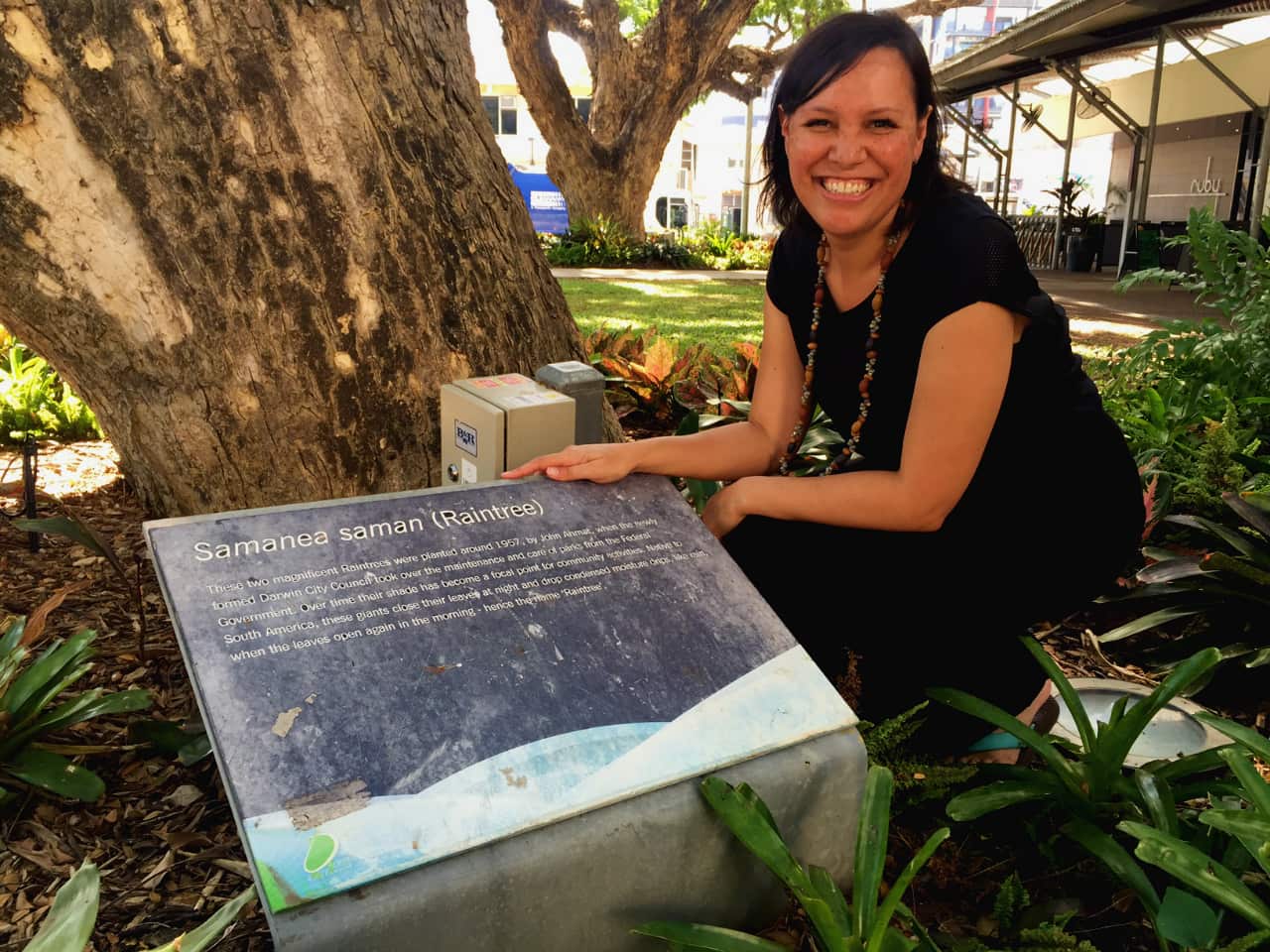 NITV News presenter Natalie Ahmat with the Raintree planted by her grandfather around 1957.